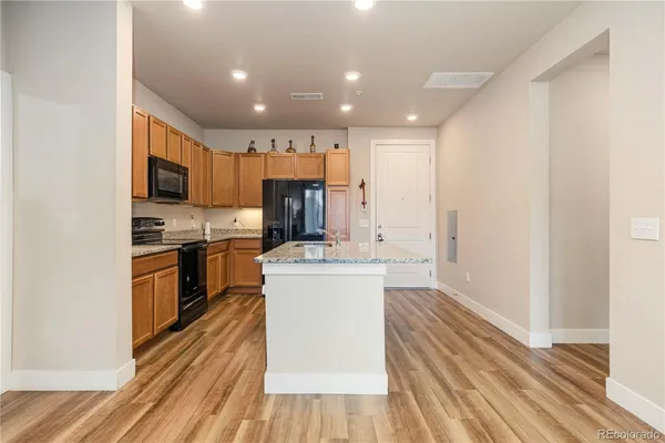 a kitchen with a sink stainless steel appliances wooden floor and a window