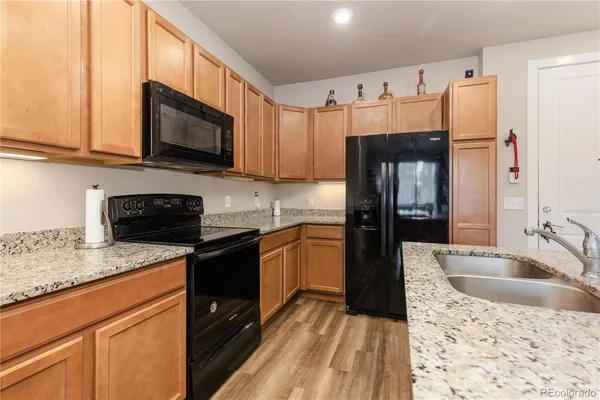 a kitchen with granite countertop a refrigerator stove and sink