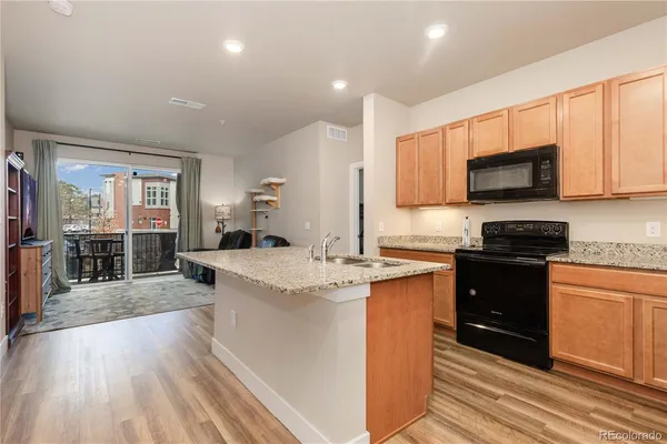 a kitchen with stainless steel appliances kitchen island granite countertop a stove top oven a sink a dining table and chairs with wooden floor