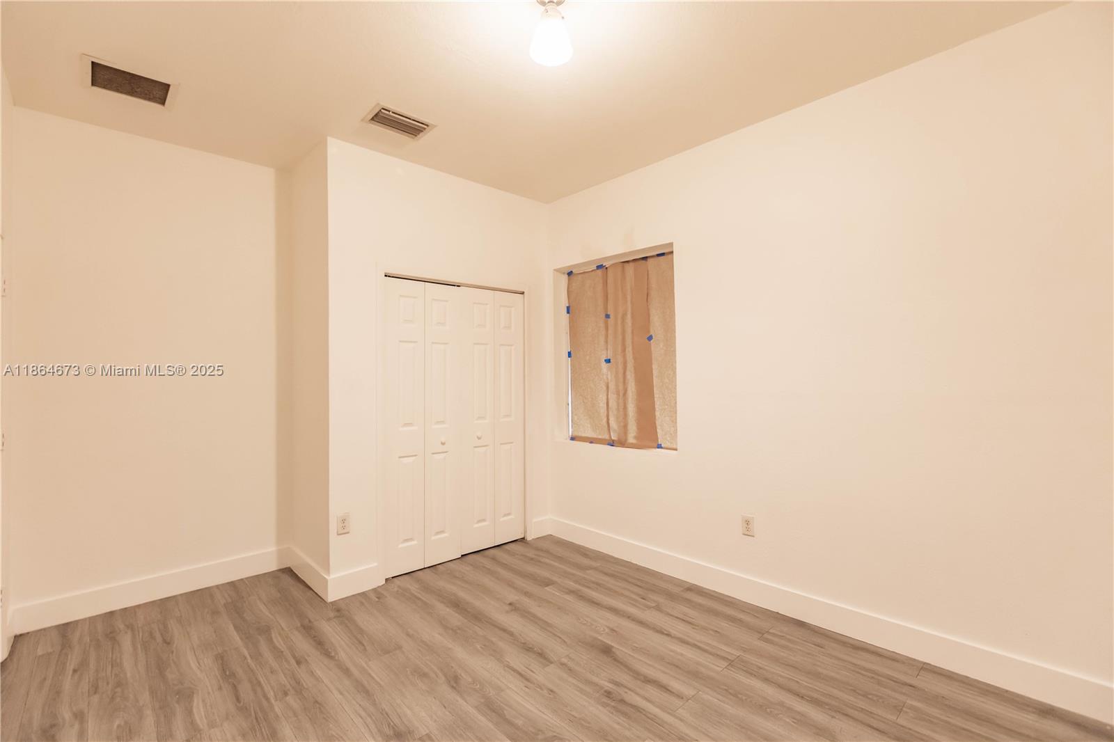 445 Northwest 77th Street, Unit 445 Miami, FL 33150 - Photo 12 of 20 a view of an empty room with wooden floor and a window