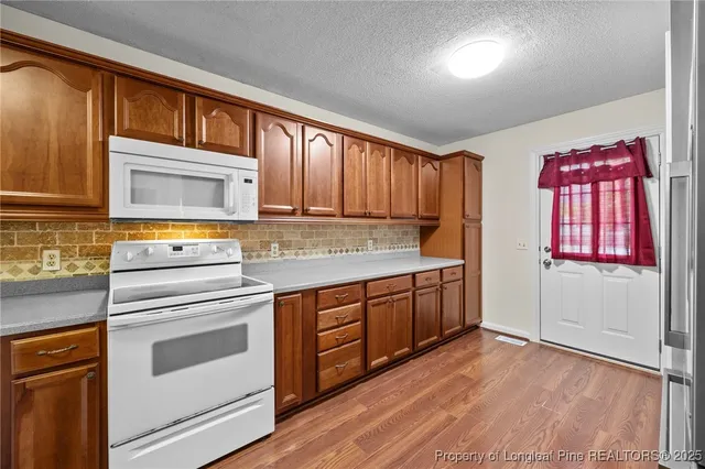 a kitchen with granite countertop wooden cabinets stainless steel appliances and a window