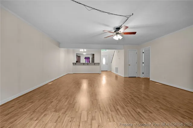 a view of empty room with wooden floor and fan