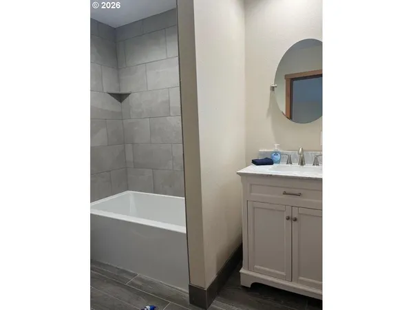 a bathroom with a bathtub sink vanity and mirror