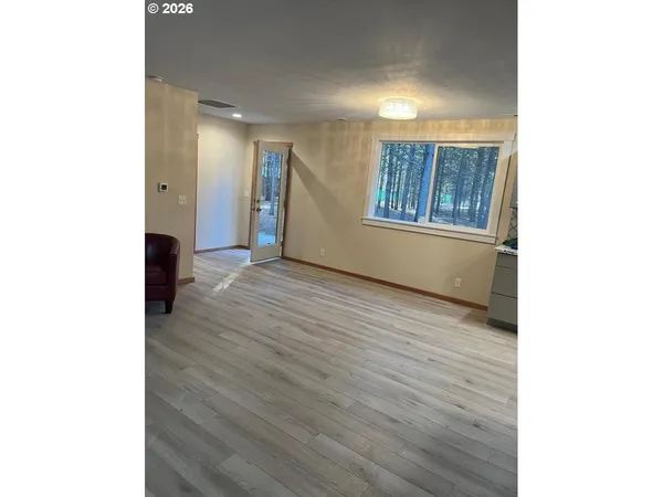 a view of an empty room with window and wooden floor