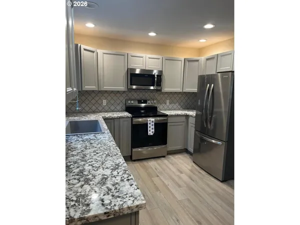 a kitchen with stainless steel appliances granite countertop a refrigerator and a stove