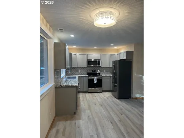 a kitchen with stainless steel appliances granite countertop a refrigerator and a stove top oven