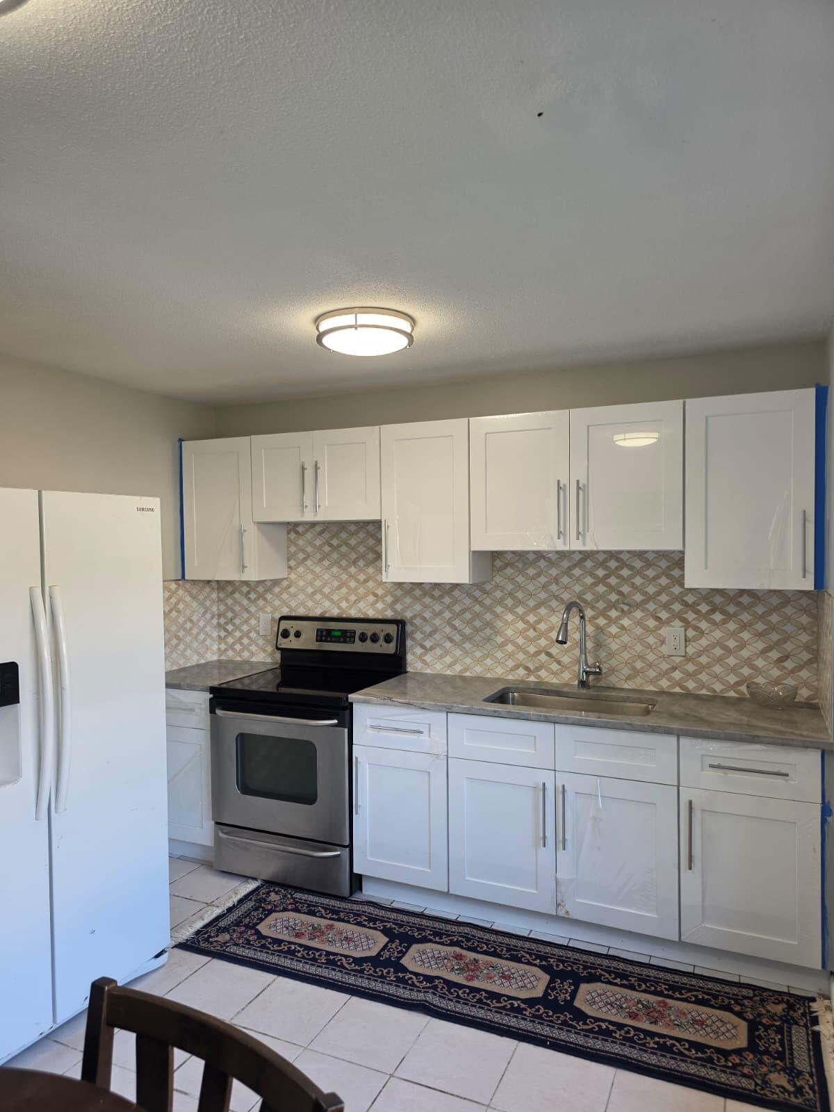 3386 Rudolph Road Lake Worth Beach, FL 33461 - Photo 12 of 25 a kitchen with granite countertop a stove a refrigerator and a white cabinets