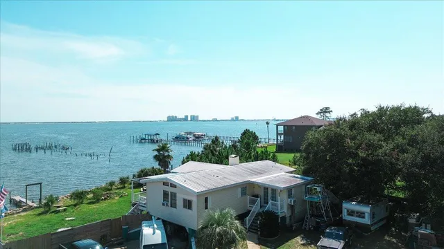 an aerial view of ocean and residential houses with outdoor space
