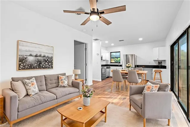 a living room with furniture kitchen view and a chandelier