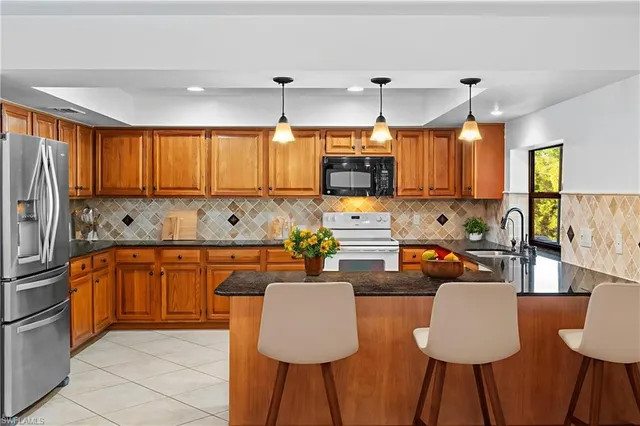 a kitchen with stainless steel appliances granite countertop a sink counter space and a refrigerator