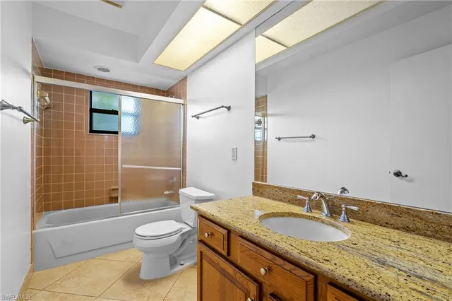 a bathroom with a granite countertop sink a toilet and shower