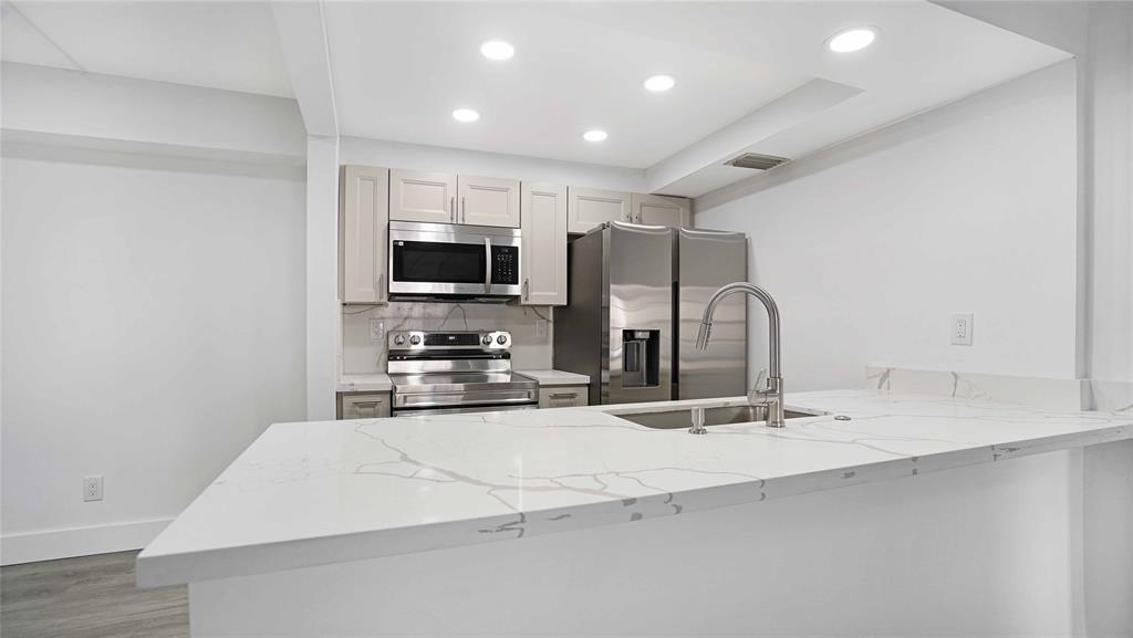 a large kitchen with kitchen island a sink stainless steel appliances and cabinets