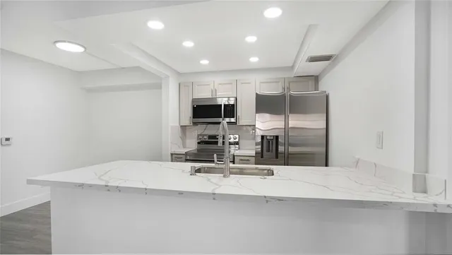 a kitchen with kitchen island a sink appliances and cabinets