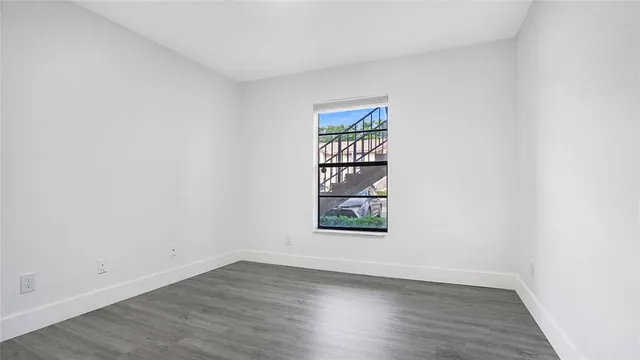 an empty room with wooden floor and window