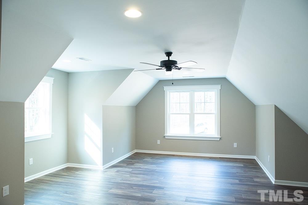 1426 Bowmantown Road Roxboro, NC 27574 - Photo 26 of 28 an empty room with wooden floor chandelier fan and windows