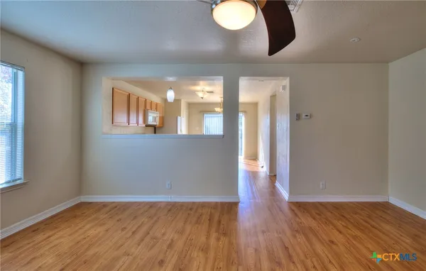 a view of an empty room with wooden floor and a window