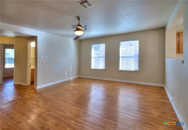 an empty room with wooden floor and windows