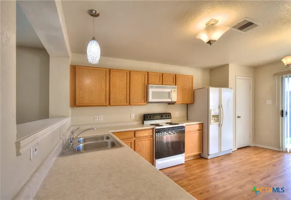 a kitchen with stainless steel appliances a stove a refrigerator a sink a stove white cabinets and wooden floor