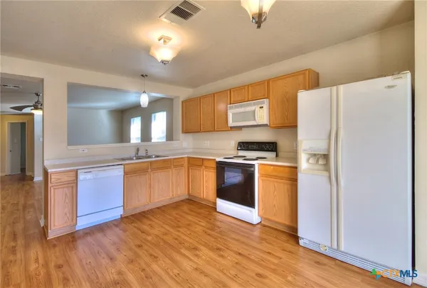 a kitchen with granite countertop a refrigerator and a stove top oven