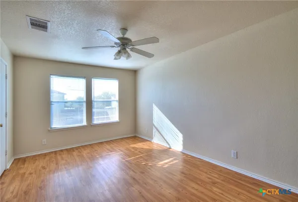 a view of empty room with wooden floor and fan