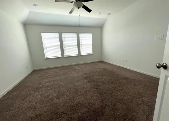 an empty room with a ceiling fan and window