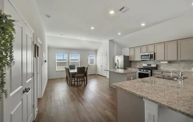 a kitchen with sink microwave refrigerator dining table and chairs
