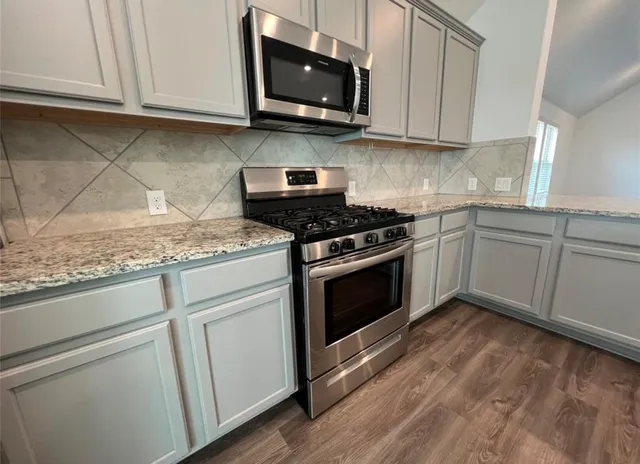 a kitchen with granite countertop white cabinets and appliances