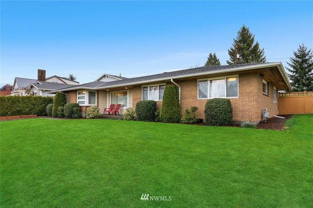a view of a yard in front of a house with plants and large tree