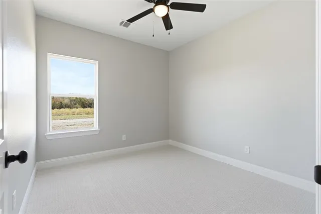 an empty room with a window and a fan