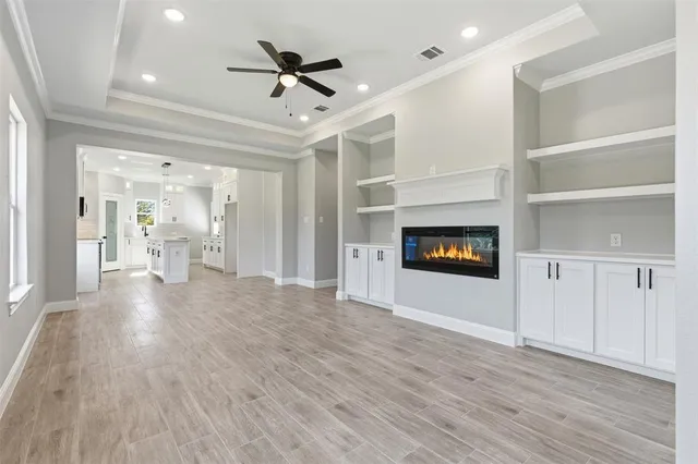 an empty room with wooden floor fireplace and windows