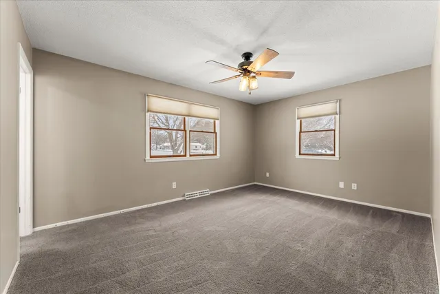 an empty room with windows and chandelier fan