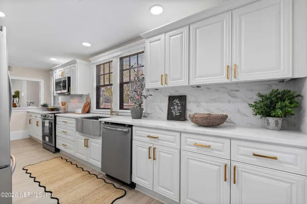 a bedroom with a bed a chair and potted plant on the dresser