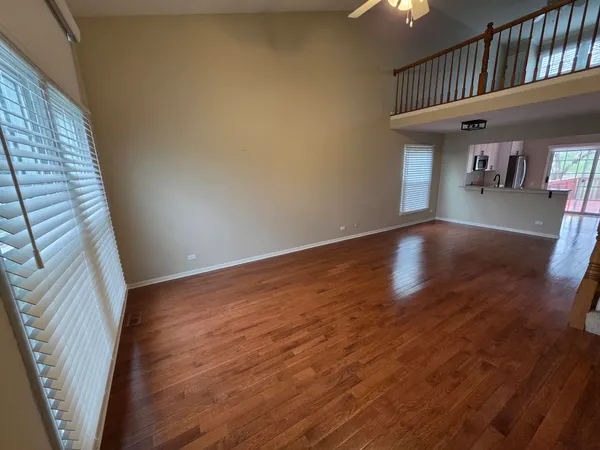 a view of an empty room with wooden floor and a book shelf