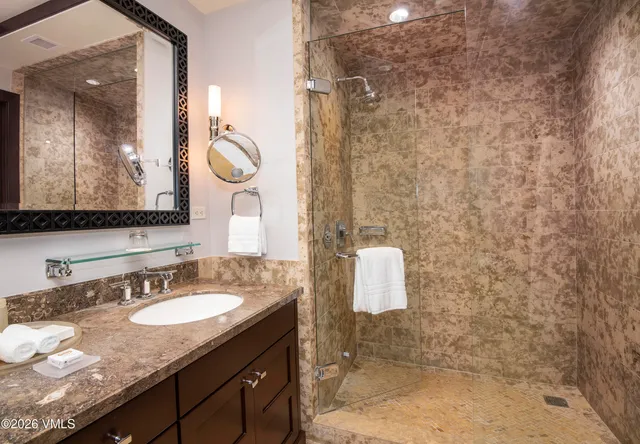a bathroom with a granite countertop sink a mirror and shower