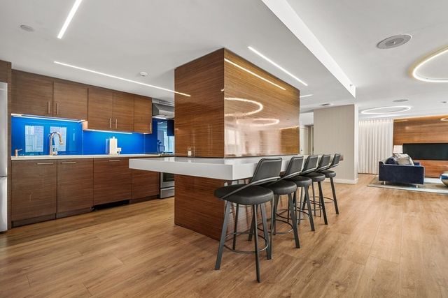 a kitchen with stainless steel appliances kitchen island granite countertop wooden floors and a view of living room