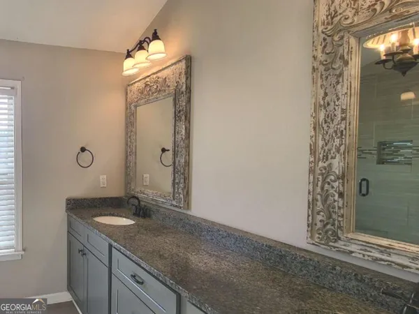a bathroom with a granite countertop sink a mirror and shower