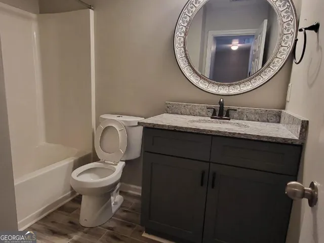a bathroom with a toilet mirror vanity and sink