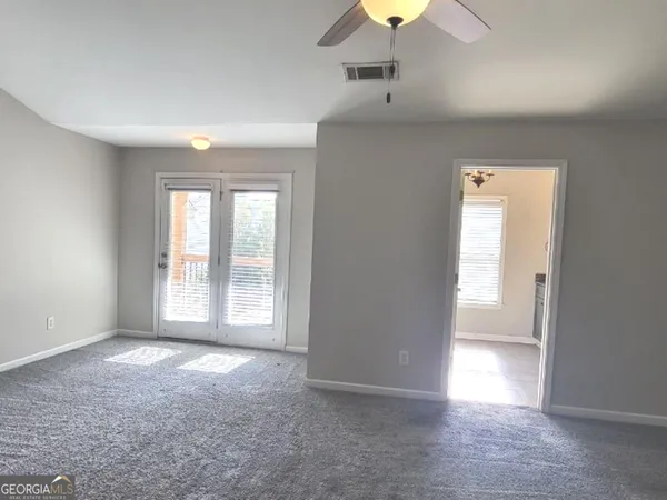 an empty room with windows and chandelier fan