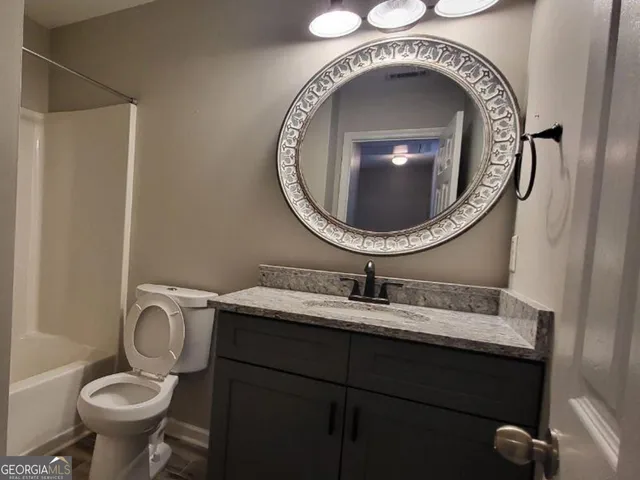 a bathroom with a granite countertop toilet sink and mirror