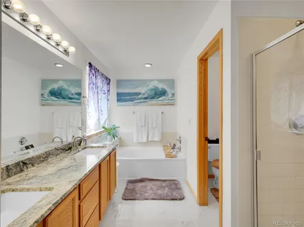 a bathroom with a granite countertop sink and a bathtub