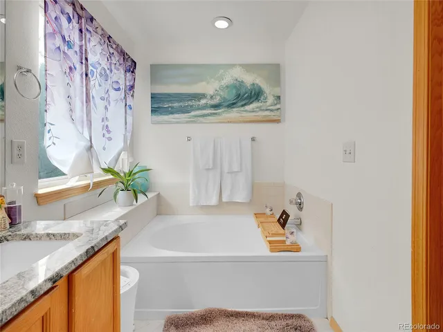 a bathroom with a granite countertop sink a large mirror and a bathtub