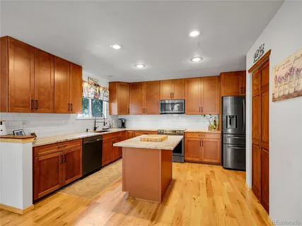 a kitchen with stainless steel appliances granite countertop wooden cabinets a sink dishwasher a refrigerator and a stove