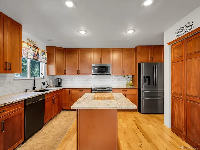 a kitchen with stainless steel appliances granite countertop refrigerator a sink a stove top oven and wooden floor