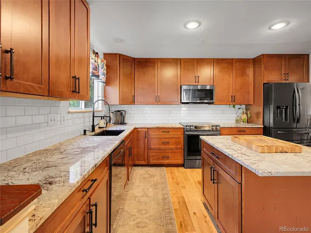 a kitchen with stainless steel appliances granite countertop wooden cabinets a stove and a sink