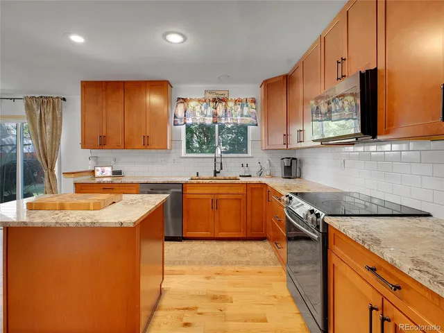 a kitchen with stainless steel appliances granite countertop a sink stove and cabinets