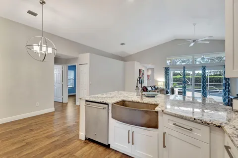 a kitchen with stainless steel appliances granite countertop a sink a stove and a wooden floors