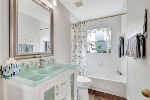 a bathroom with a granite countertop sink a toilet a mirror a vanity and shower