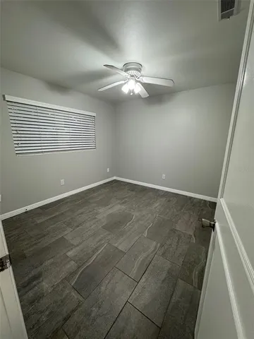 an empty room with ceiling fan and window