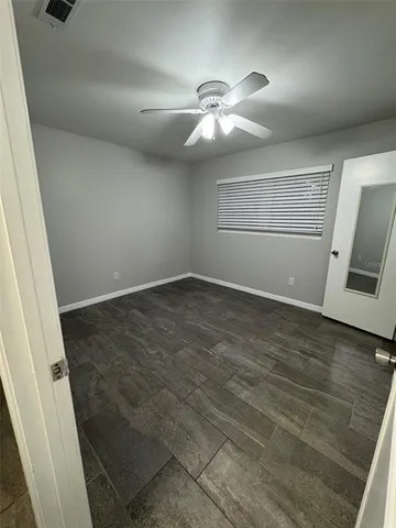 an empty room with wooden floor and fan