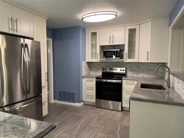 a kitchen with granite countertop a refrigerator stove and microwave